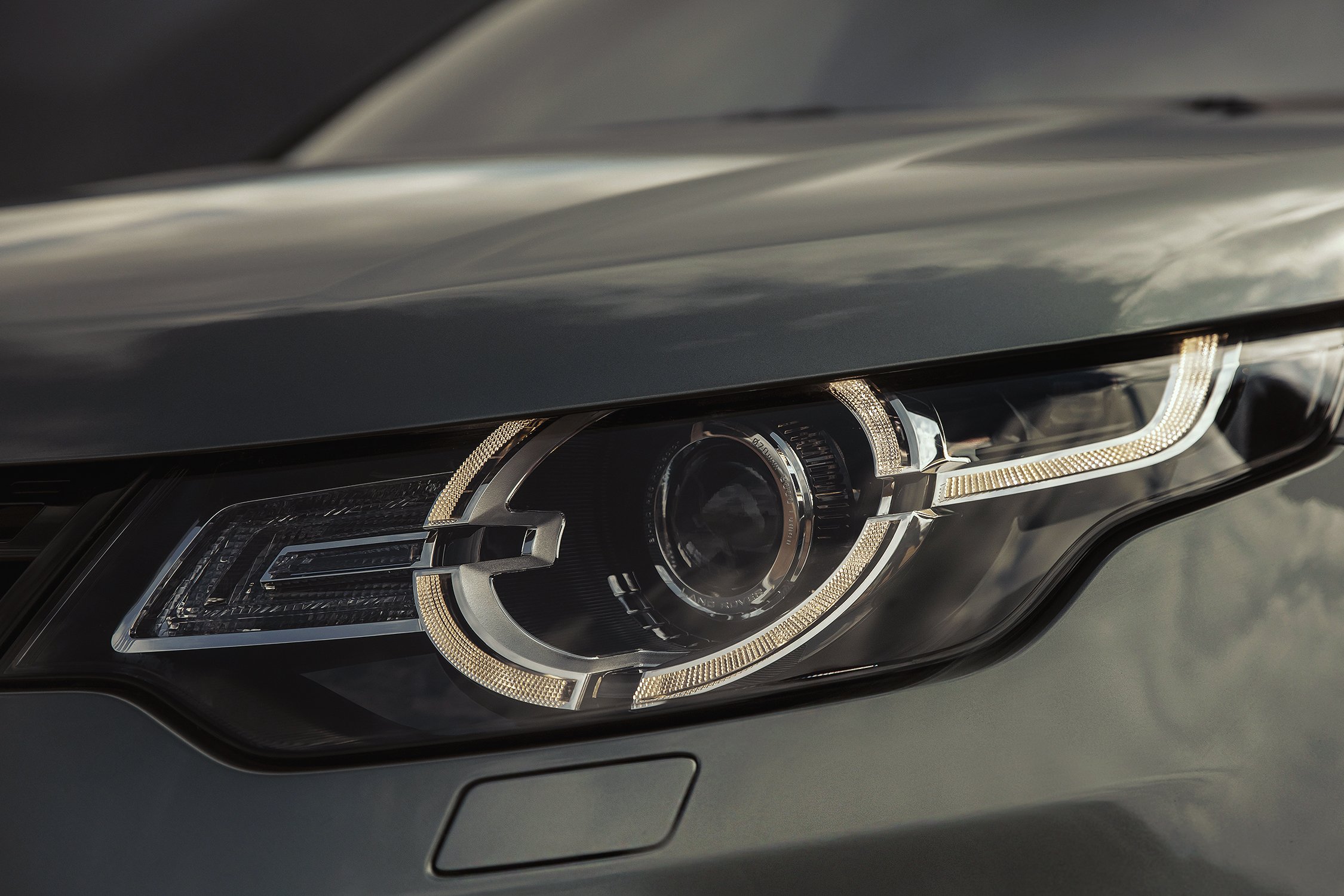 Close-up of a Land Rover Discovery car headlight with intricate LED details and a sleek, modern design reflecting automotive engineering.