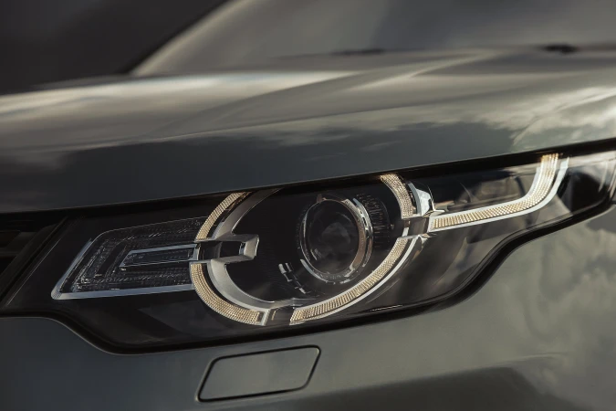 Close-up of a Land Rover Discovery car headlight with intricate LED details and a sleek, modern design reflecting automotive engineering.