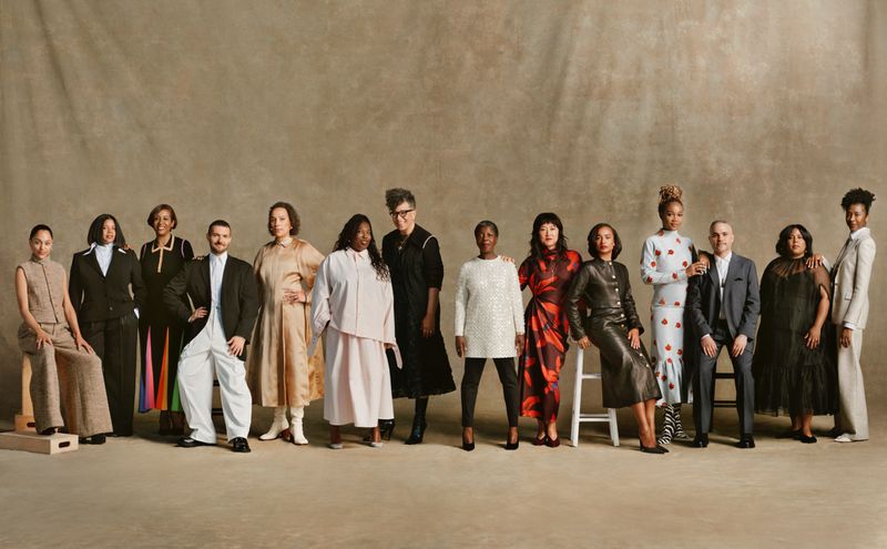 A group of fourteen diverse adult models stand in a studio, posing in various fashions against a neutral backdrop, showcasing an array of styles.