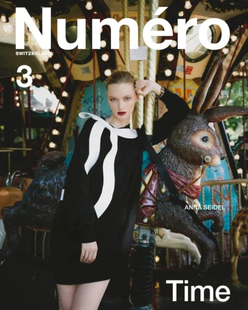 Magazine cover featuring a woman in a black dress with a white bow, standing next to a carousel bunny in an outdoor setting.