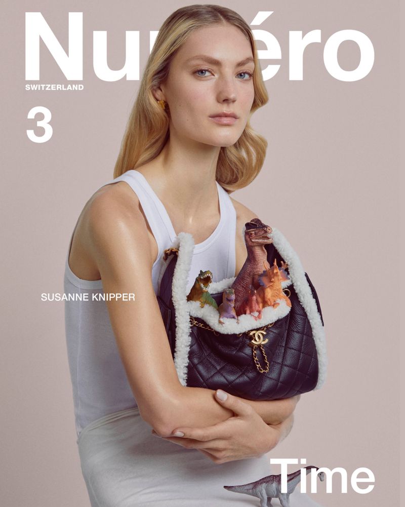 Magazine cover featuring a fair-skinned model in a white tank top holding a black Chanel purse filled with toy dinosaurs.