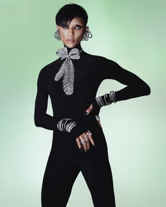 Georgia Palmer poses in a black high-neck catsuit and crystal Swarovski jewelry against a soft green studio backdrop.