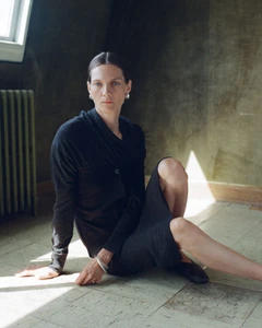 Model Karolin Wolter seated on a tiled floor wearing a black top and skirt for Soeur F/W 2025 Campaign