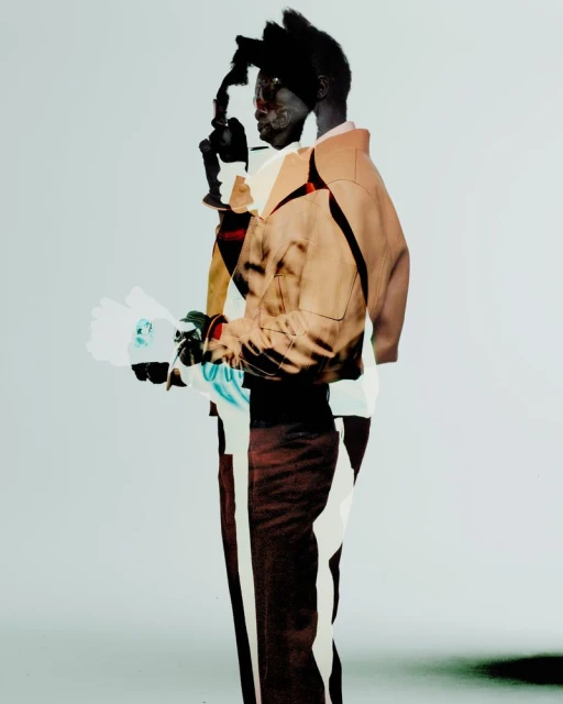 Double exposure portrait of an African American adult male model with modern tan coat and flowers set against a pale gradient background.