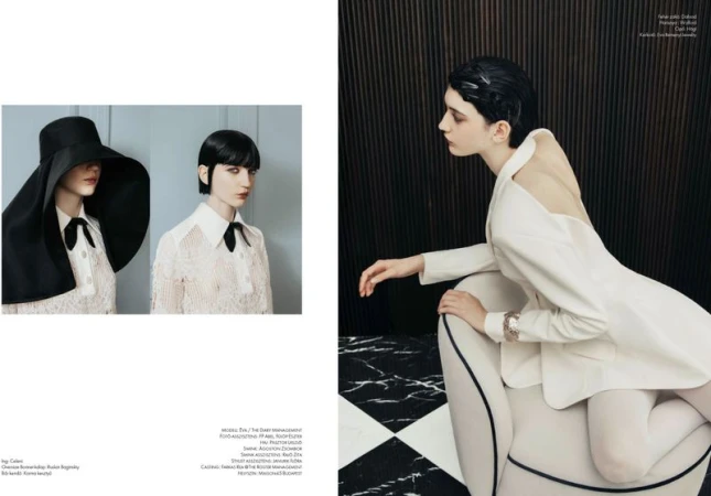 Fashion editorial featuring a dark-haired woman in a white blazer and hosiery, seated indoors with geometric patterned background.