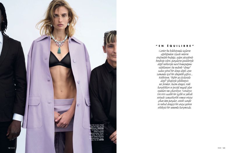 Fashion editorial shot of an adult female in an open lilac coat and black bra posing with two adult humans on a white background.