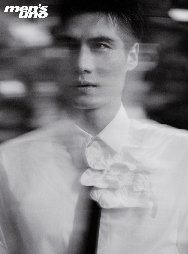 Monochrome portrait of a stylish man in a white shirt with a frilled collar and tie, captured with a motion blur effect.