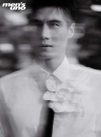 Monochrome portrait of a stylish man in a white shirt with a frilled collar and tie, captured with a motion blur effect.