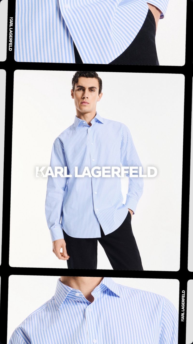 A brunette male fashion model wearing a blue striped button-down shirt and black pants, posing against a seamless white backdrop.