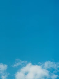 Bright blue sky with soft white clouds along the lower edge in vertical composition.