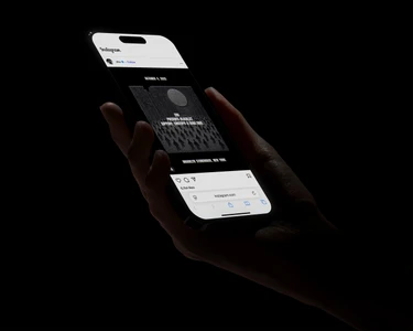 Close-up of hands holding a smartphone displaying an Instagram post against a dark background
