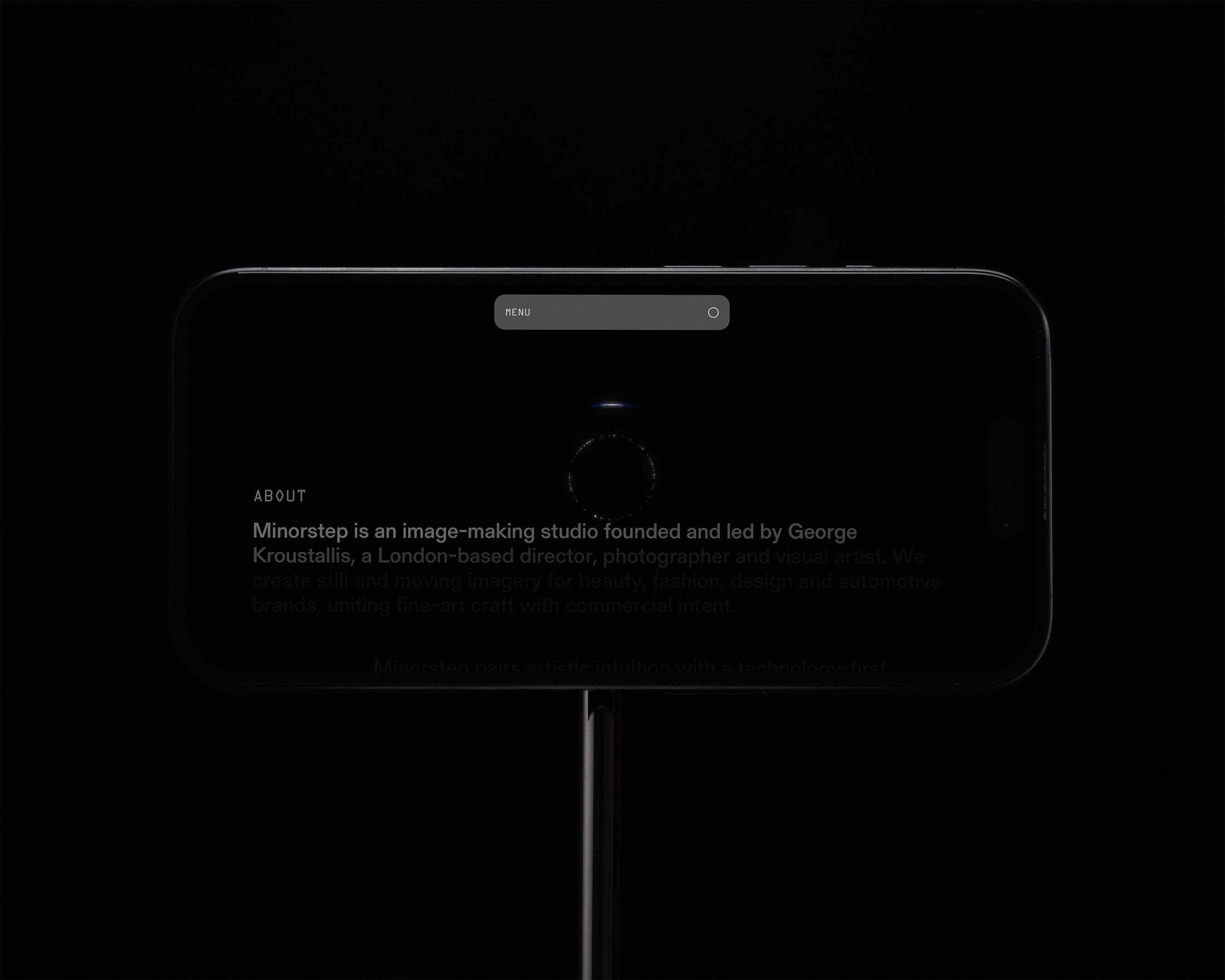 Dark mode rendering of a website's 'About' page on a mobile device, illuminated against a black background on a dark pole.