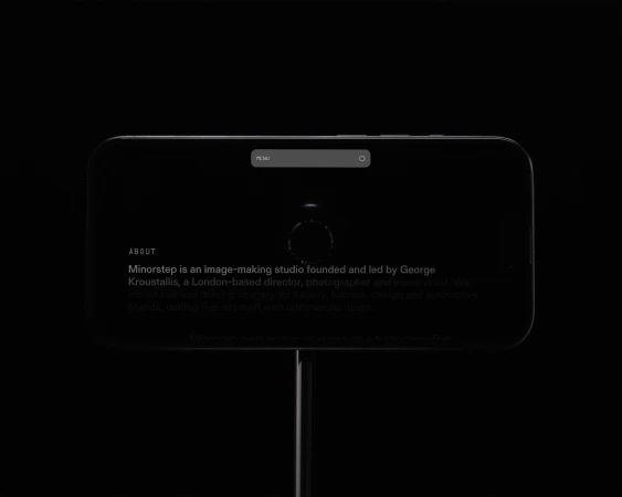 Dark mode rendering of a website's 'About' page on a mobile device, illuminated against a black background on a dark pole.