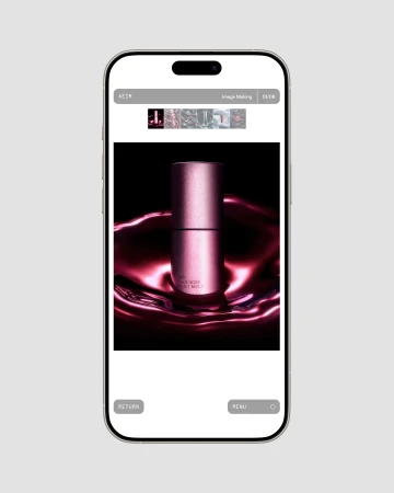 Image on a smartphone screen shows a pink cosmetic product with light reflecting off a dark fluid-like surface, beauty shot.
