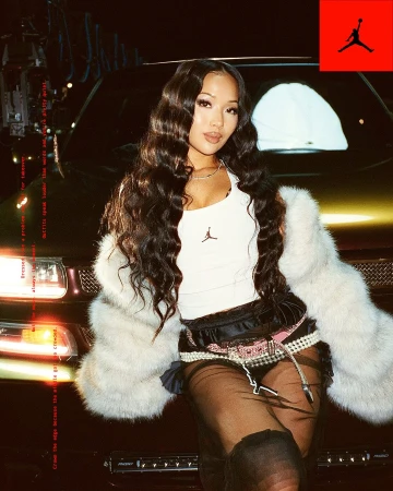 Attractive Asian woman with long wavy hair poses in a faux fur coat and modern clothing, leaning on a metallic gold SUV car.