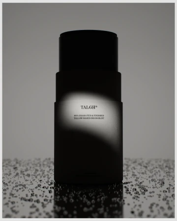 Minimalist studio shot of black deodorant stick with product details against a neutral background with water droplet effect.