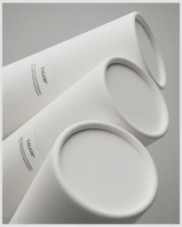 Three cylindrical white Talgh deodorant packaging tubes angled diagonally on a neutral grey background