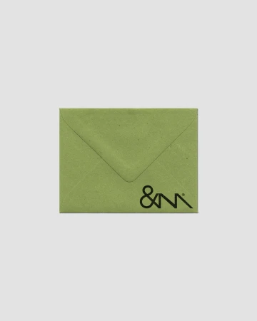 Close-up of a light green envelope with a simple logo in the lower corner, set against a neutral gray background in portrait layout.