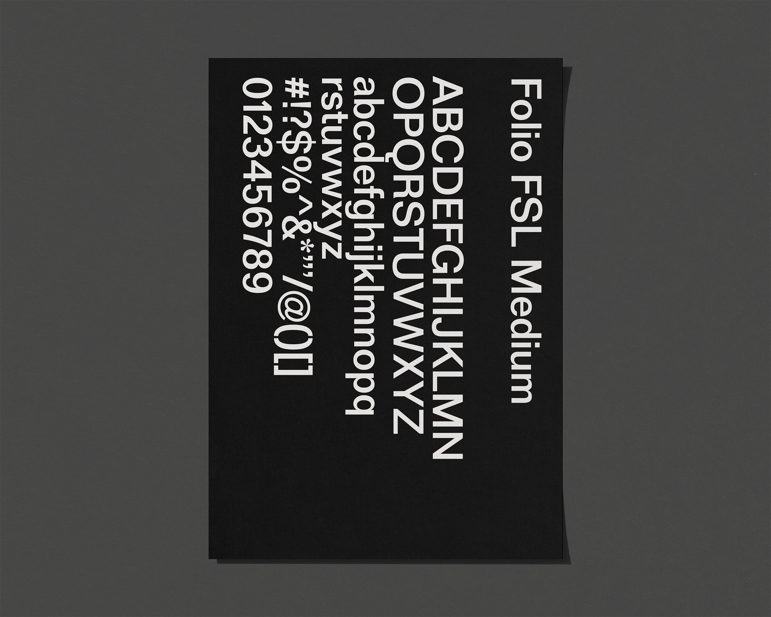 Black card with white text displaying the Folio FSL Medium font including uppercase and lowercase alphabets, numbers, and symbols.