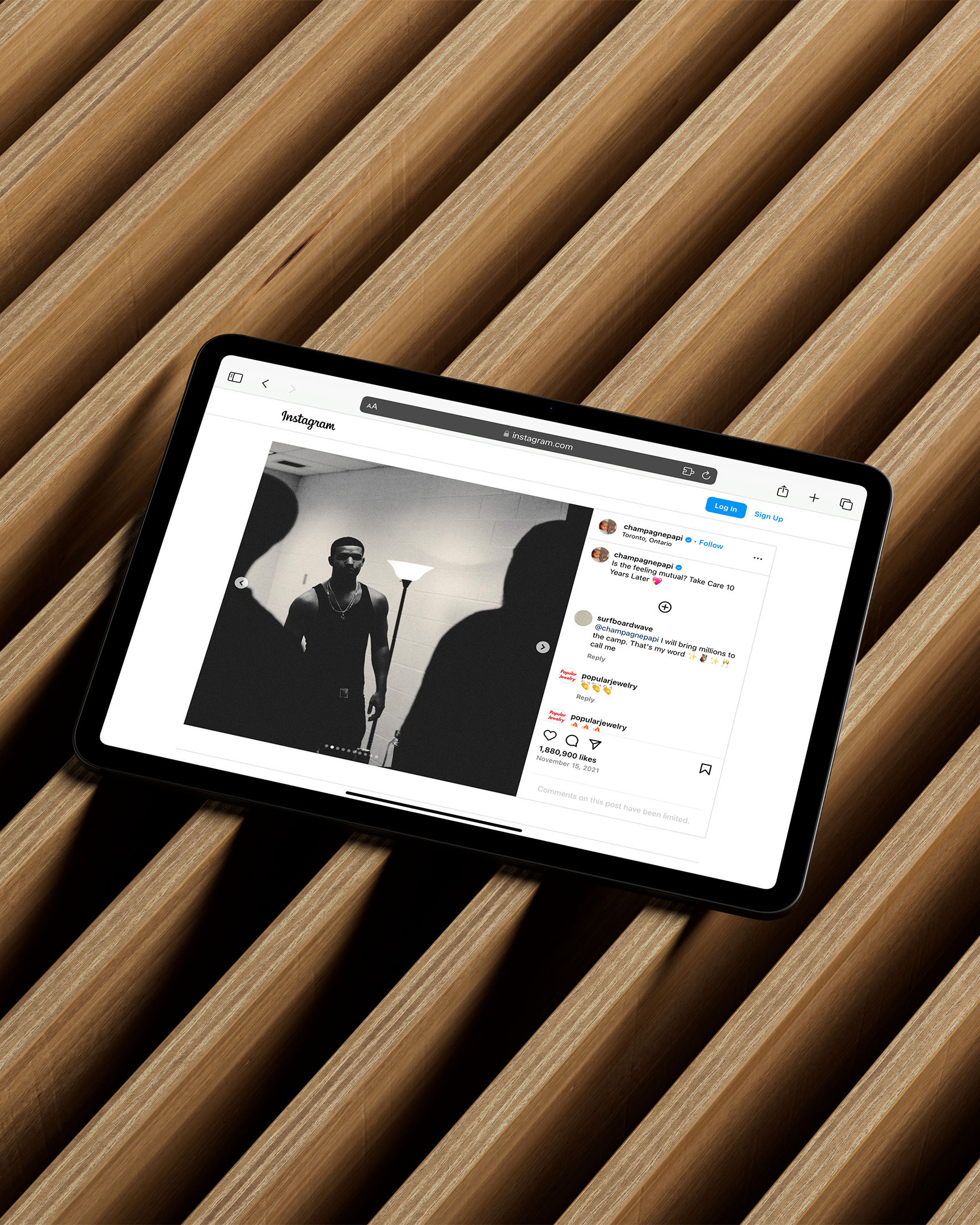 Tablet displays an Instagram page featuring a black and white photo of a man, set against a textured brown wood background.