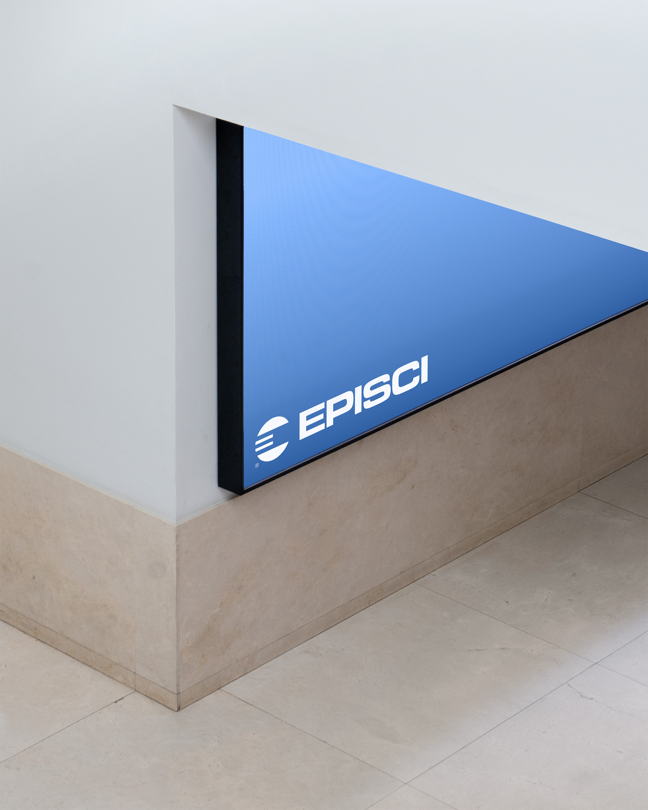 Indoor shot of a triangular blue sign displaying the word EPISCI in white, positioned on a wall with beige tile accents and flooring.