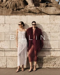 Two female models posing in front of a stone wall, wearing sunglasses and high heels for Billini.