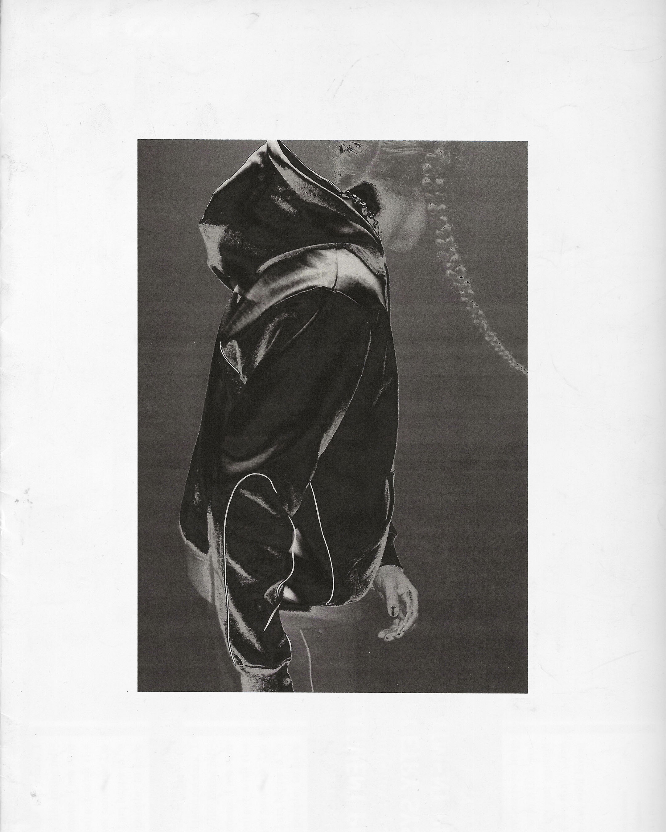 Abstract black and white photo of a person in a dark hooded sweatshirt against a neutral background, side view.
