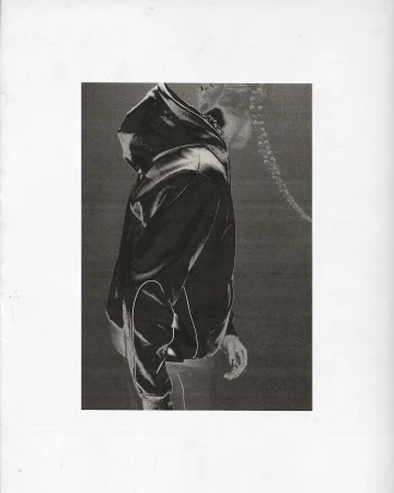 Abstract black and white photo of a person in a dark hooded sweatshirt against a neutral background, side view.