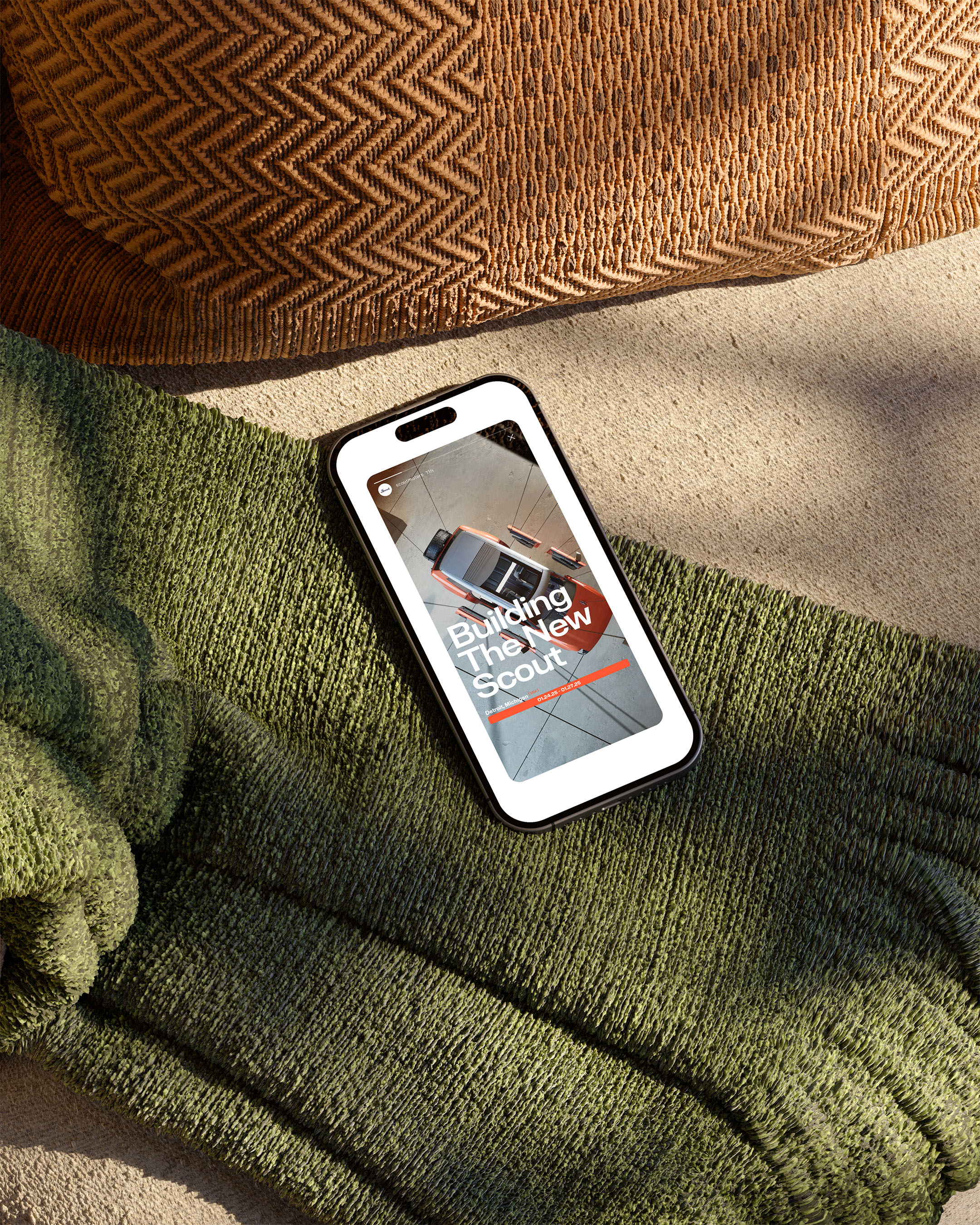 Smartphone displays an advertisement for the new Scout vehicle; close-up shot with a textured throw and cushion in the background.