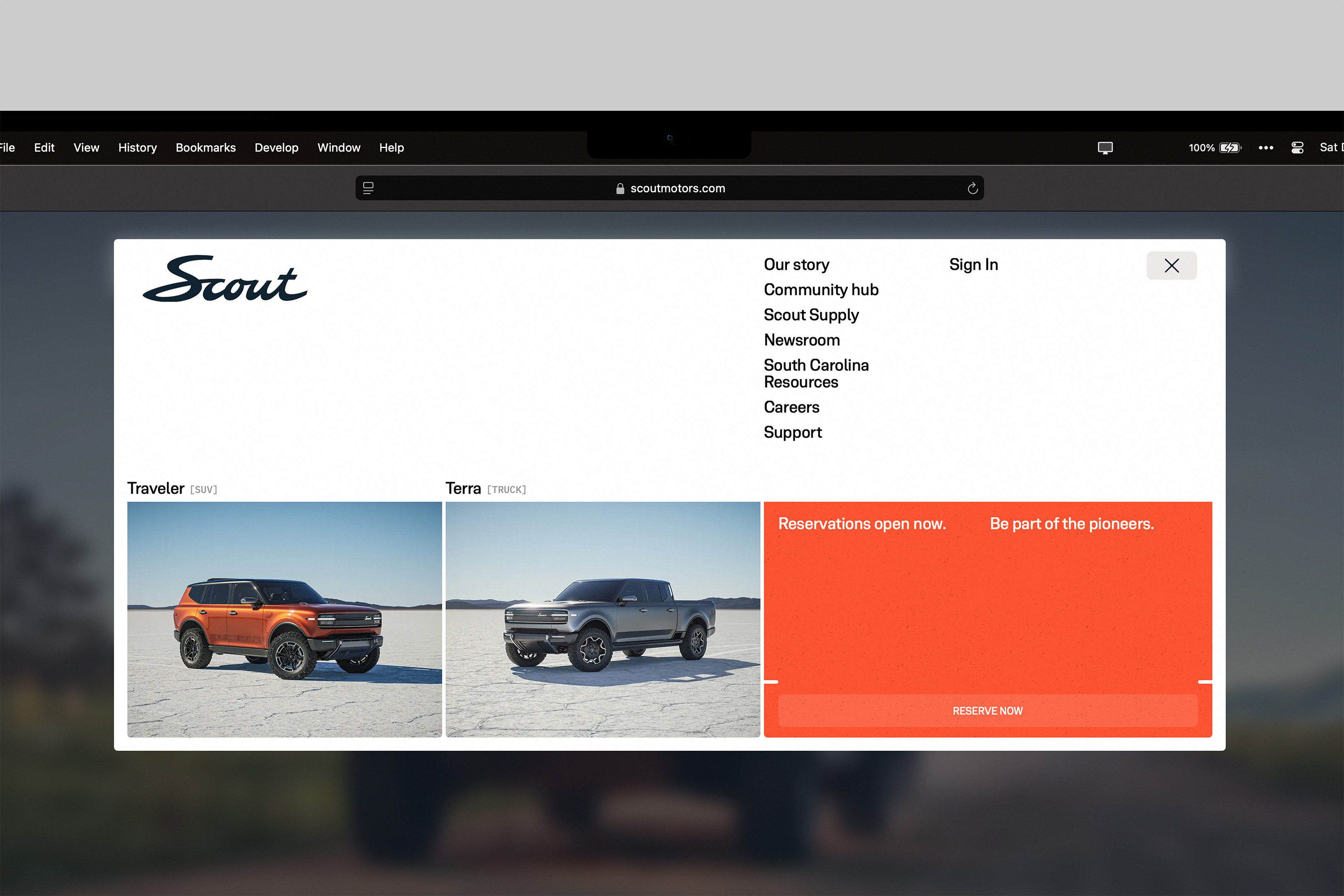 Scout Motors website showcasing the Traveler SUV and Terra truck, with navigation menu and reservation information on a blurred background.