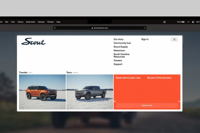 Scout Motors website showcasing the Traveler SUV and Terra truck, with navigation menu and reservation information on a blurred background.