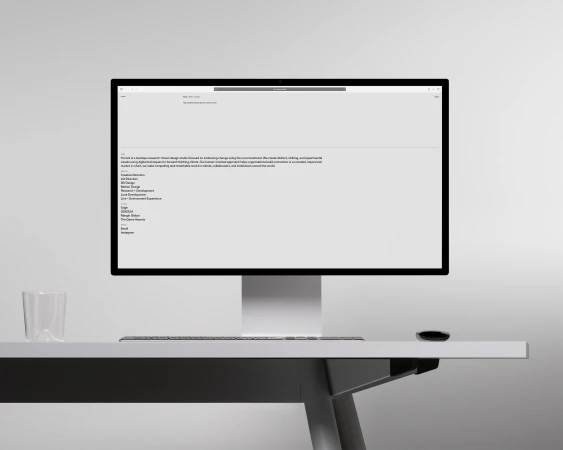 Computer monitor displaying a webpage with text, sitting on a white desk with a clear glass, a mouse, and a light grey background.