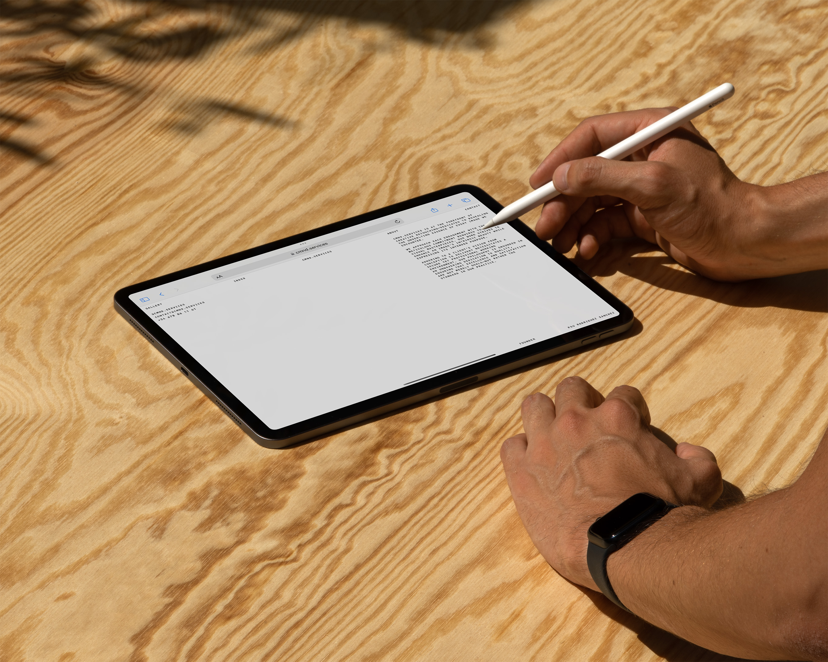 An adult uses a stylus on a digital tablet on a wooden surface in a bright setting, showcasing technology and modern communication.