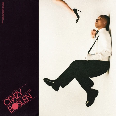 Stylish portrait of a seated man in a suit, accented by a poised stiletto heel, set against a stark white backdrop.