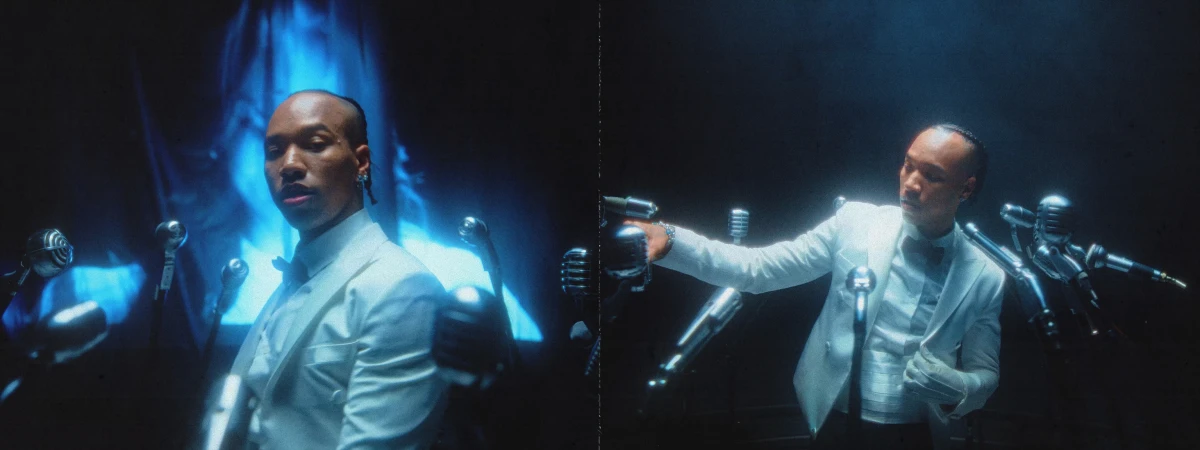 An African American man in a white tuxedo stands in front of vintage microphones, creating a classic performance atmosphere.