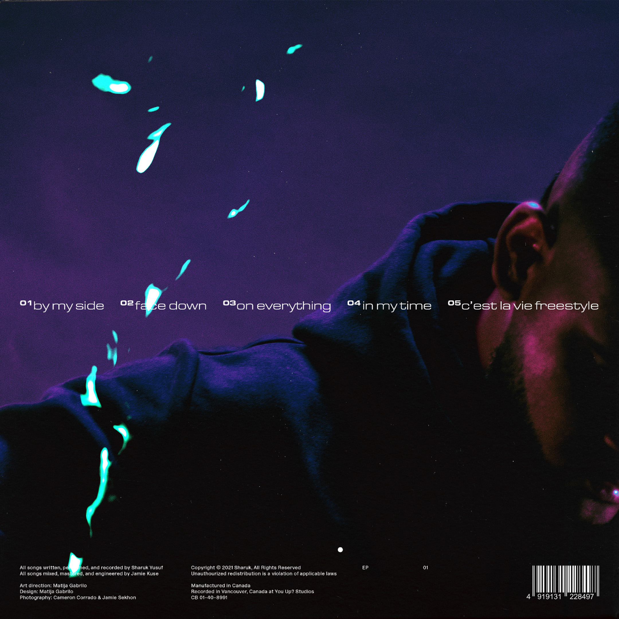 Close-up of a vinyl record cover featuring a man's face in shadow and the album title track list with bright blue light effects.