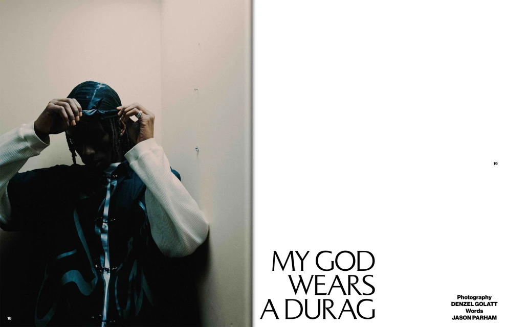 Editorial fashion portrait of an androgynous person wearing a white waffle weave shirt and a blue buttoned vest and a durag indoors.