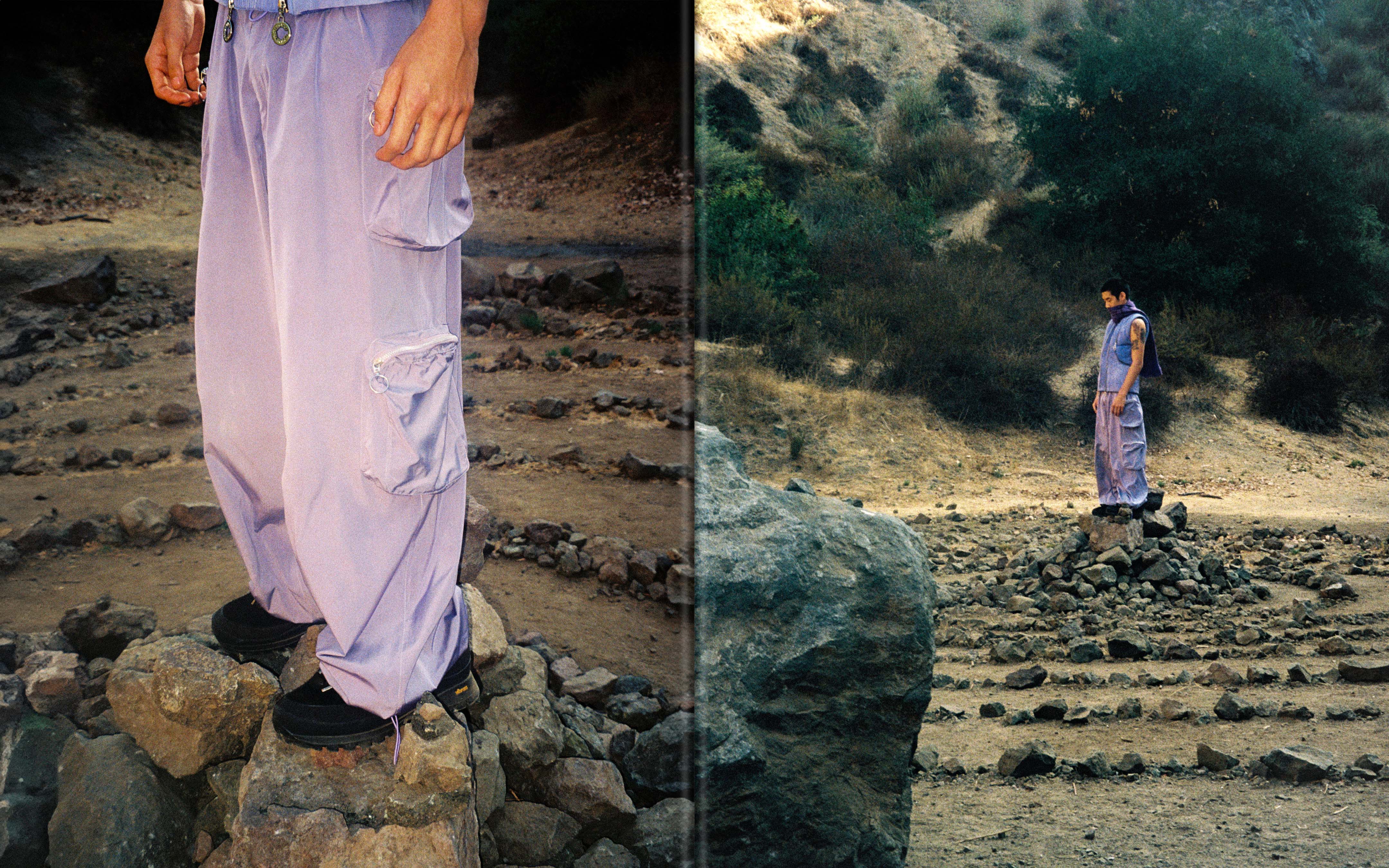 A person in lilac pants standing on rocks surrounded by a stone labyrinth in a rugged outdoor environment with natural lighting.