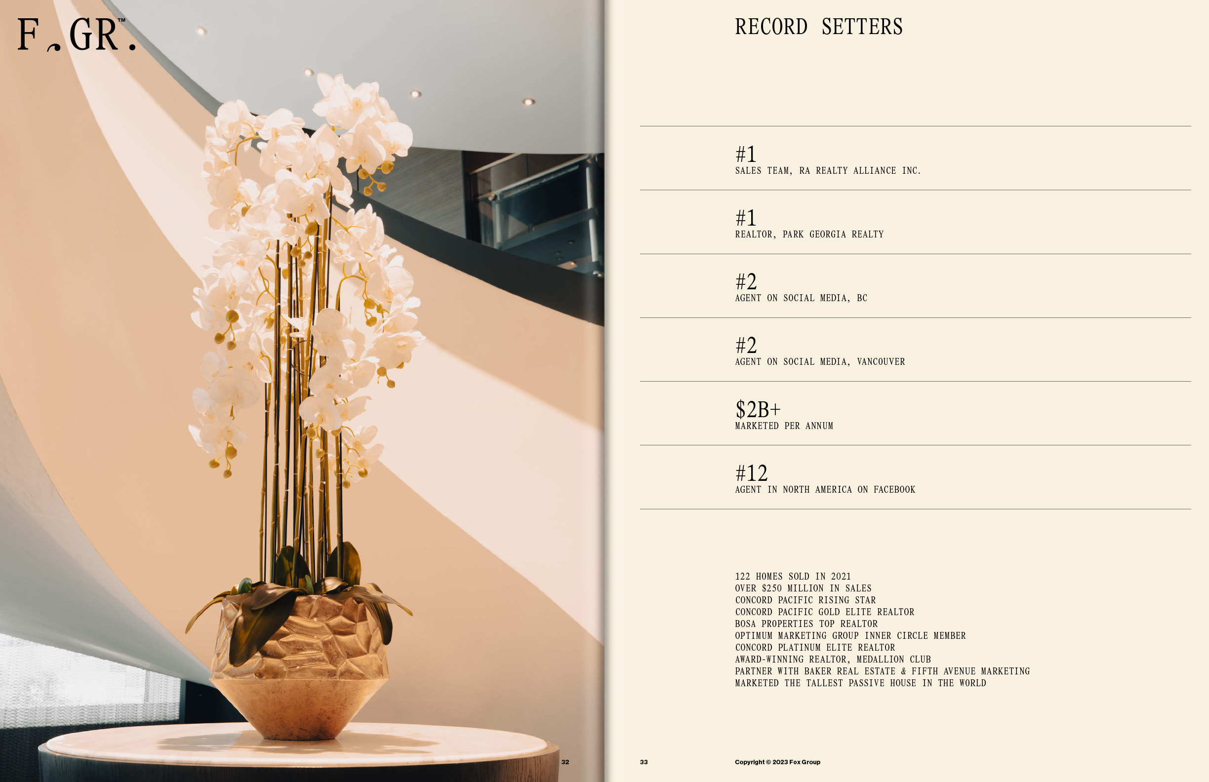 Elegant indoor floral arrangement featuring white orchids in a faceted vase with golden reeds, set against a neutral wall.