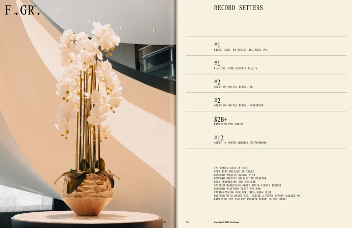 Elegant indoor floral arrangement featuring white orchids in a faceted vase with golden reeds, set against a neutral wall.