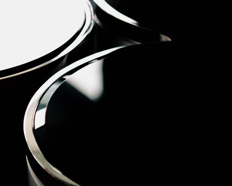 Abstract minimalist shot: Curved chrome lines contrast against a solid black backdrop. Modern design evokes sleekness and sophistication.