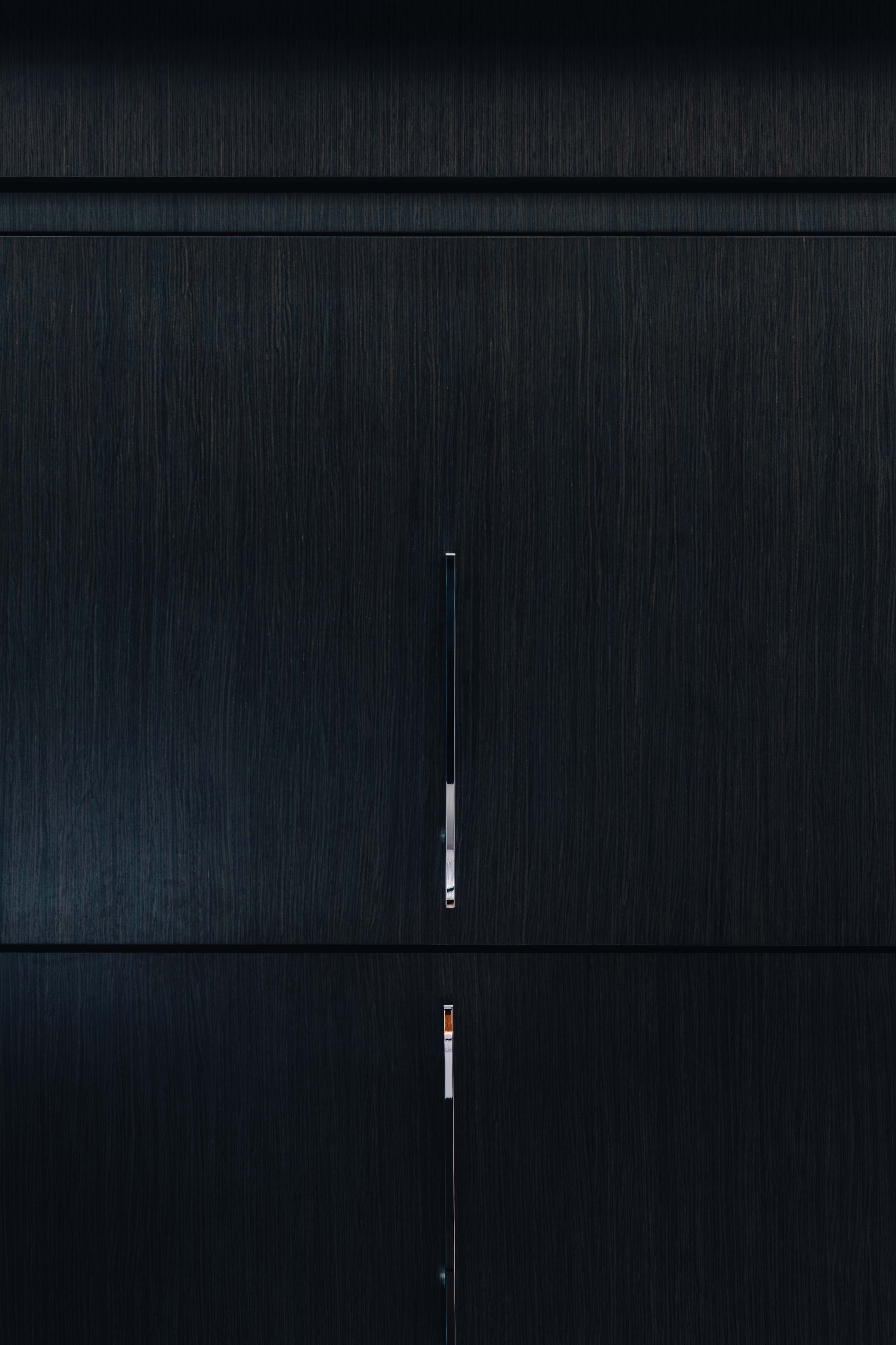 Close-up of a sleek, dark grey cabinet with minimalist, silver hardware and clean lines, showcasing modern furniture design.