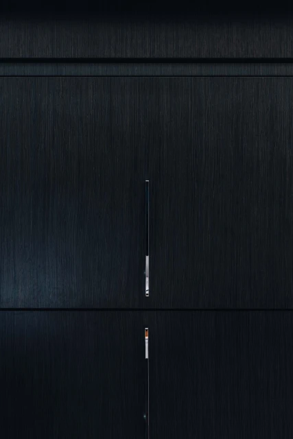 Close-up of a sleek, dark grey cabinet with minimalist, silver hardware and clean lines, showcasing modern furniture design.