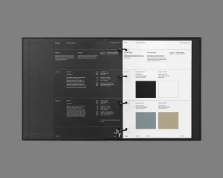Open ring-bound brand guideline book displaying typography rules on a black page and color swatches on a white page.
