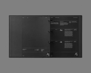 Open black ring-bound visual identity manual displaying typography guidelines against a minimal grey background.