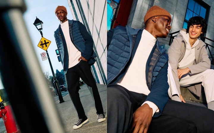 Two men in stylish outerwear stand and sit outdoors in an urban setting. One man models a blue quilted jacket and the other wears grey.