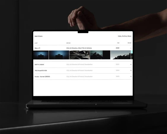 Laptop display showing a website portfolio with various design projects, including automotive visuals, in a dark, modern setting.