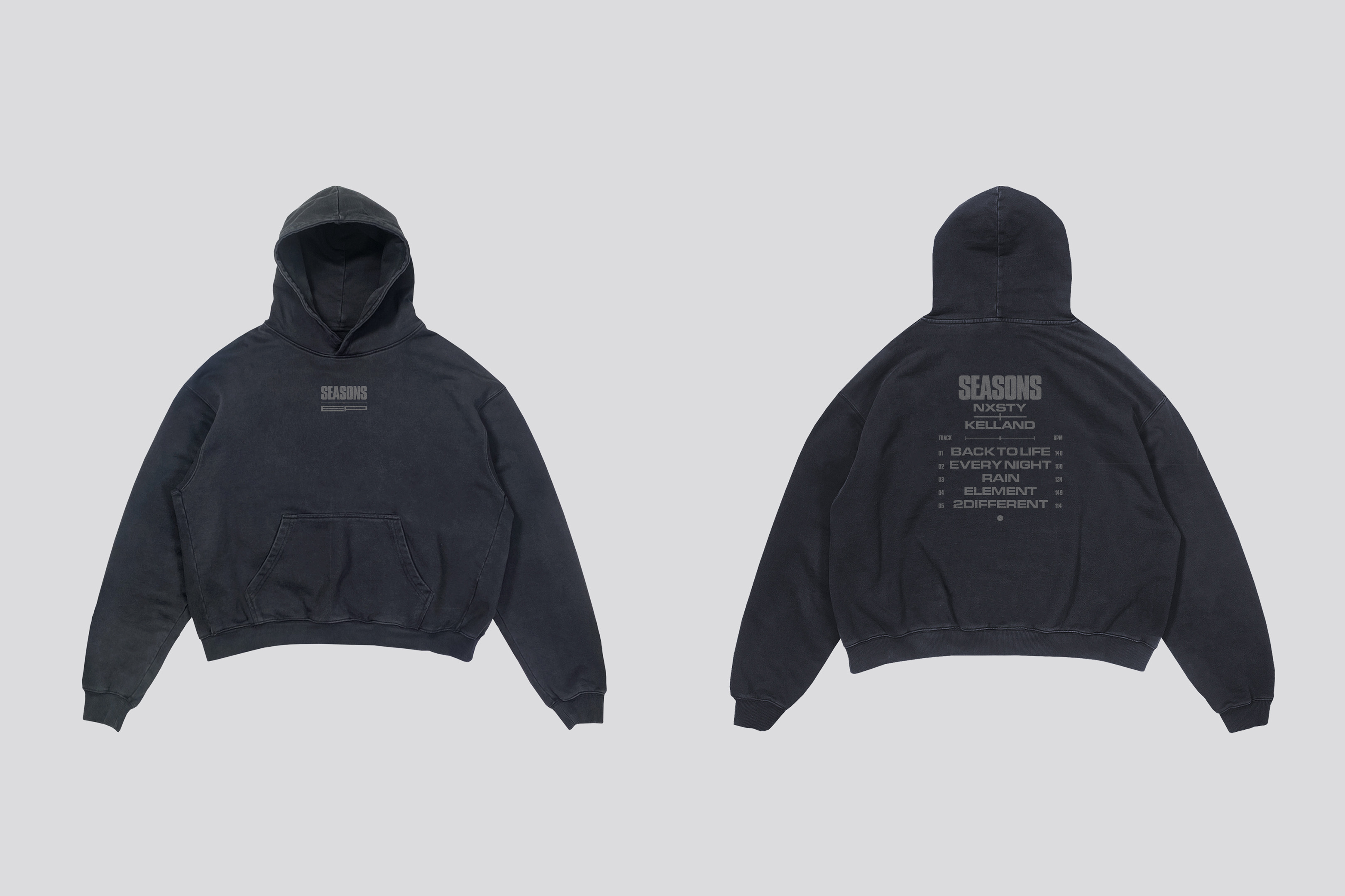 Two dark-gray hooded sweatshirts, one facing forward and one facing back, displayed on a light-gray studio backdrop with soft, neutral lighting.