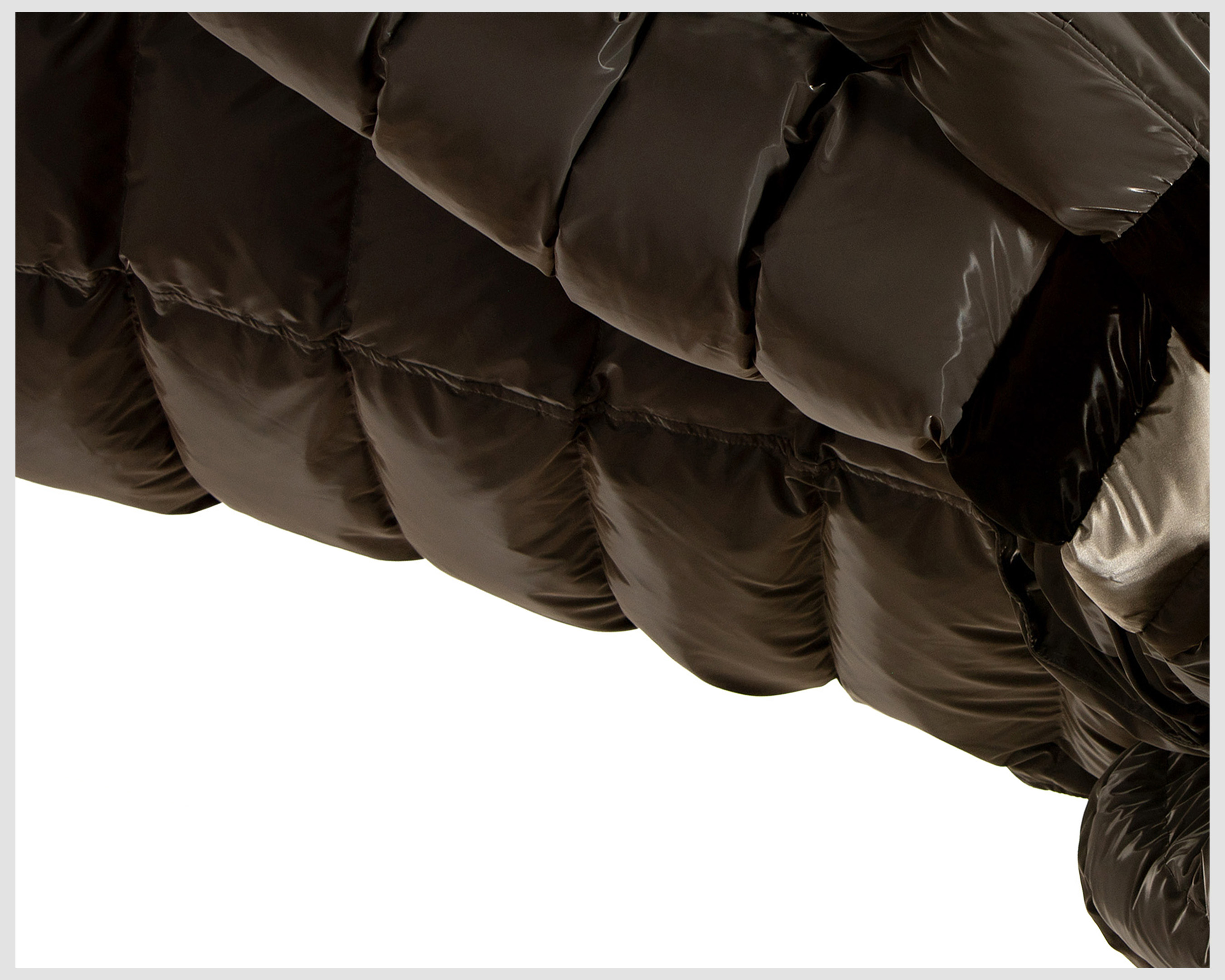 Close-up of a glossy, olive green puffer jacket with visible seams and puffy sections against a white background.