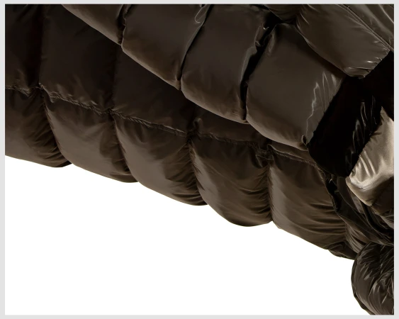 Close-up of a glossy, olive green puffer jacket with visible seams and puffy sections against a white background.